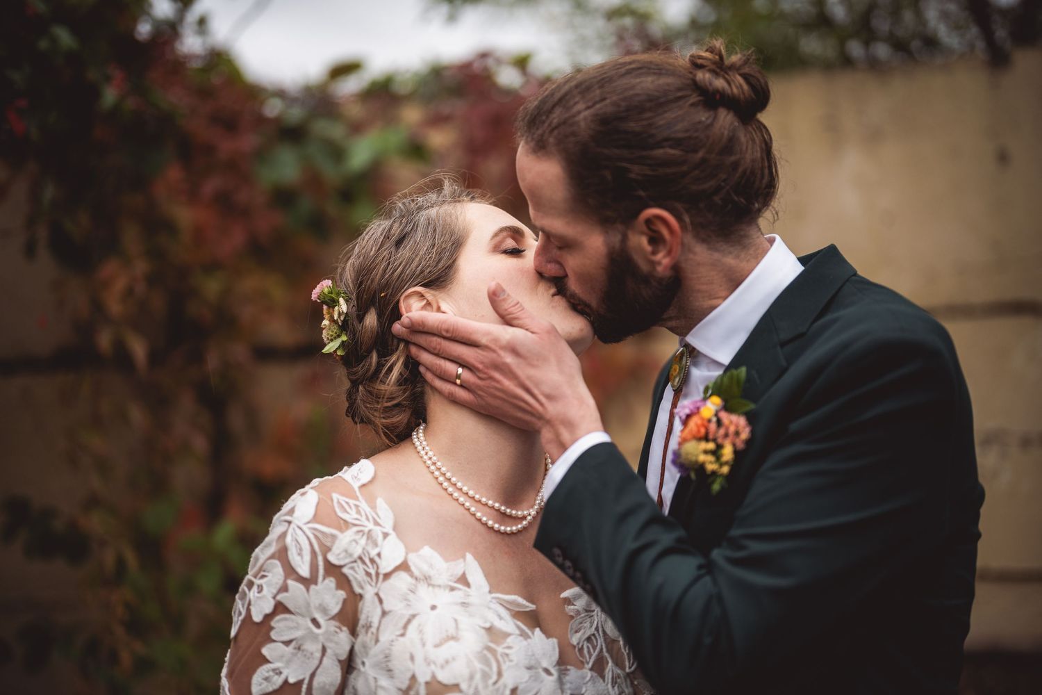 Romantic autumn wedding portrait against red foliage background.