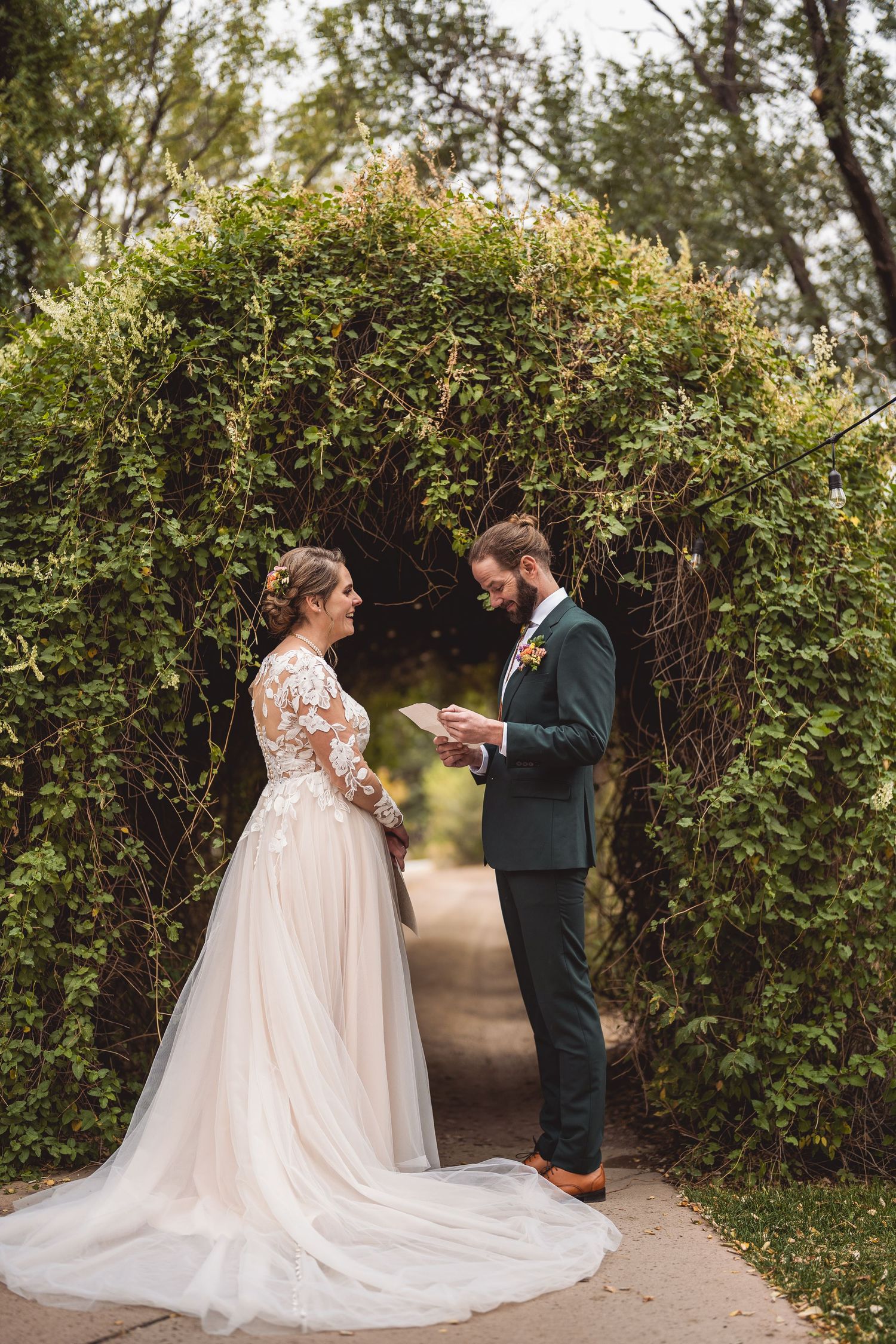 A couple poses together on a garden path surrounded by lush greenery during their wedding.