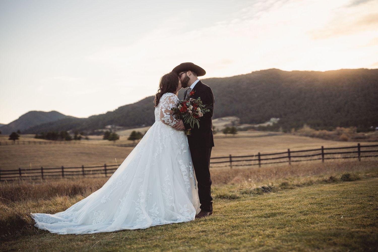 Golden hour wedding photos in mountain landscape with couple embracing.