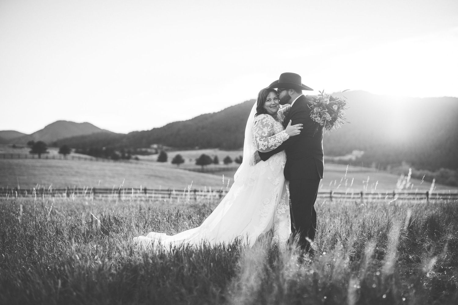 A romantic sunset photo session in a field showing a bride and groom near mountains.
