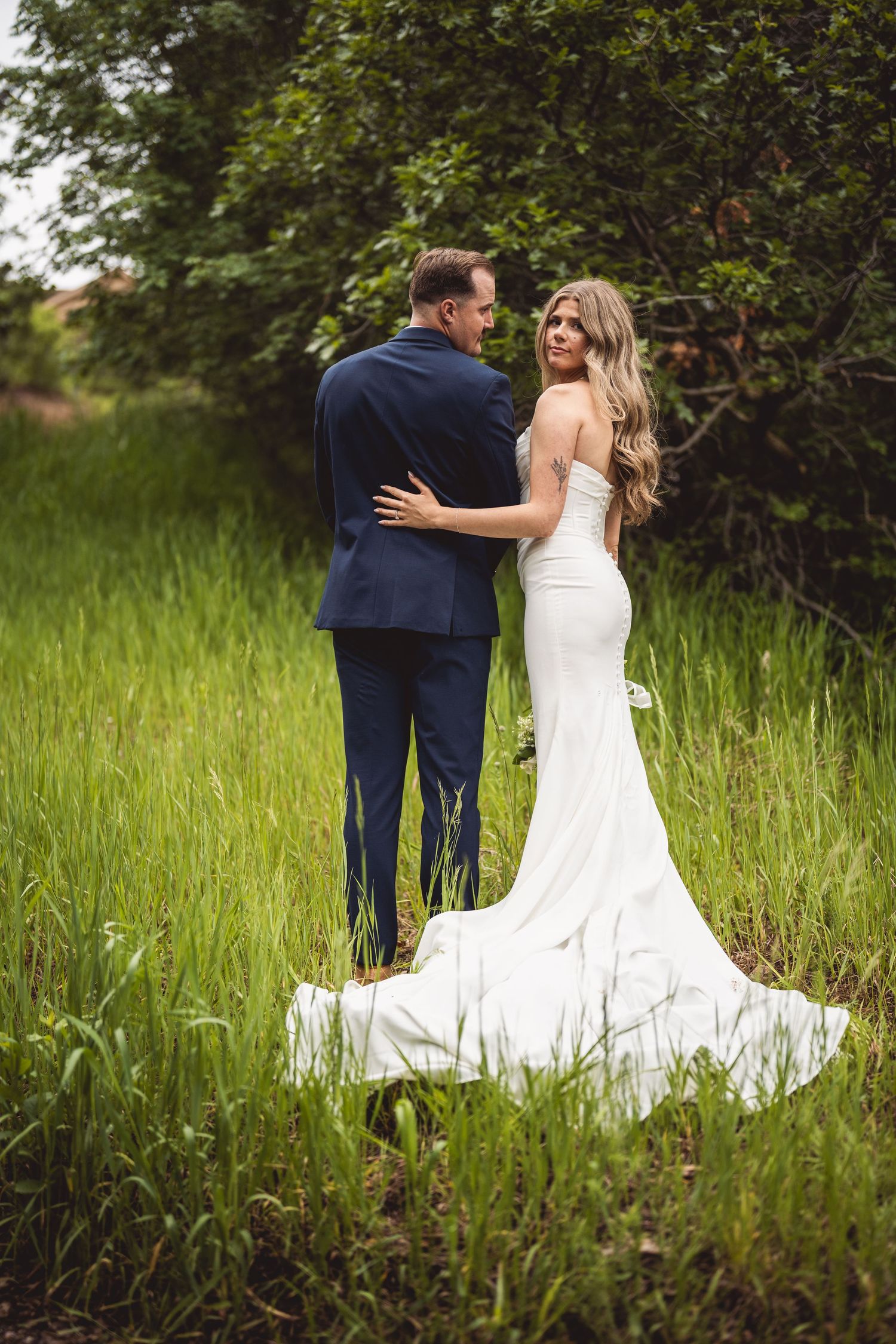 A romantic wedding photoshoot sequence showing a couple embracing in a green meadow.