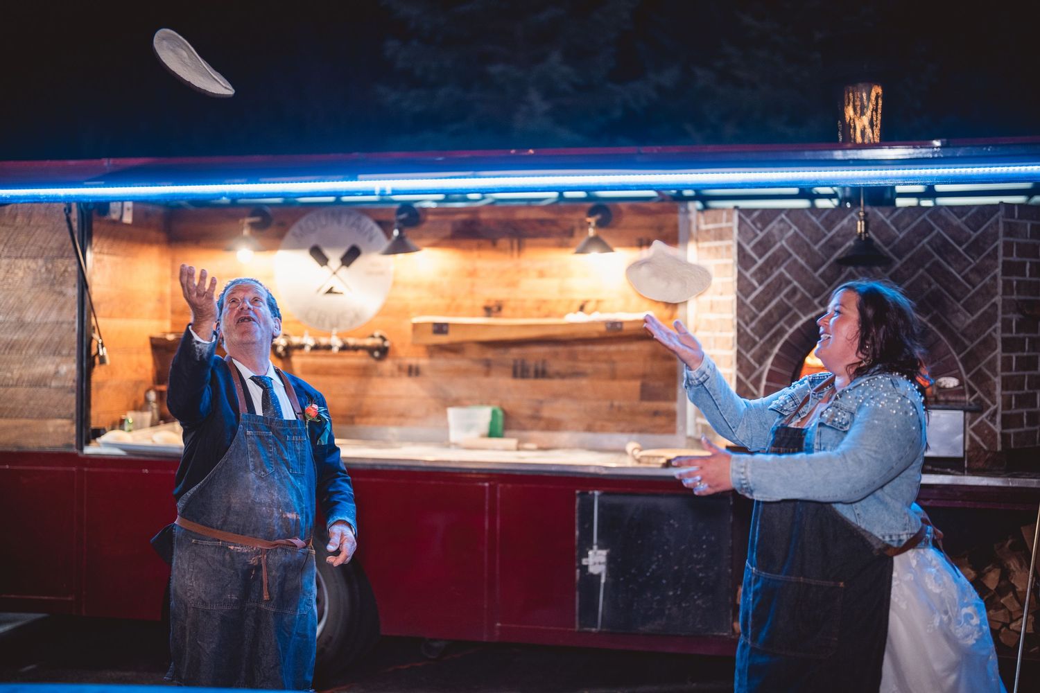 Guests enjoying food and drinks at a rustic wooden bar with blue neon lighting.