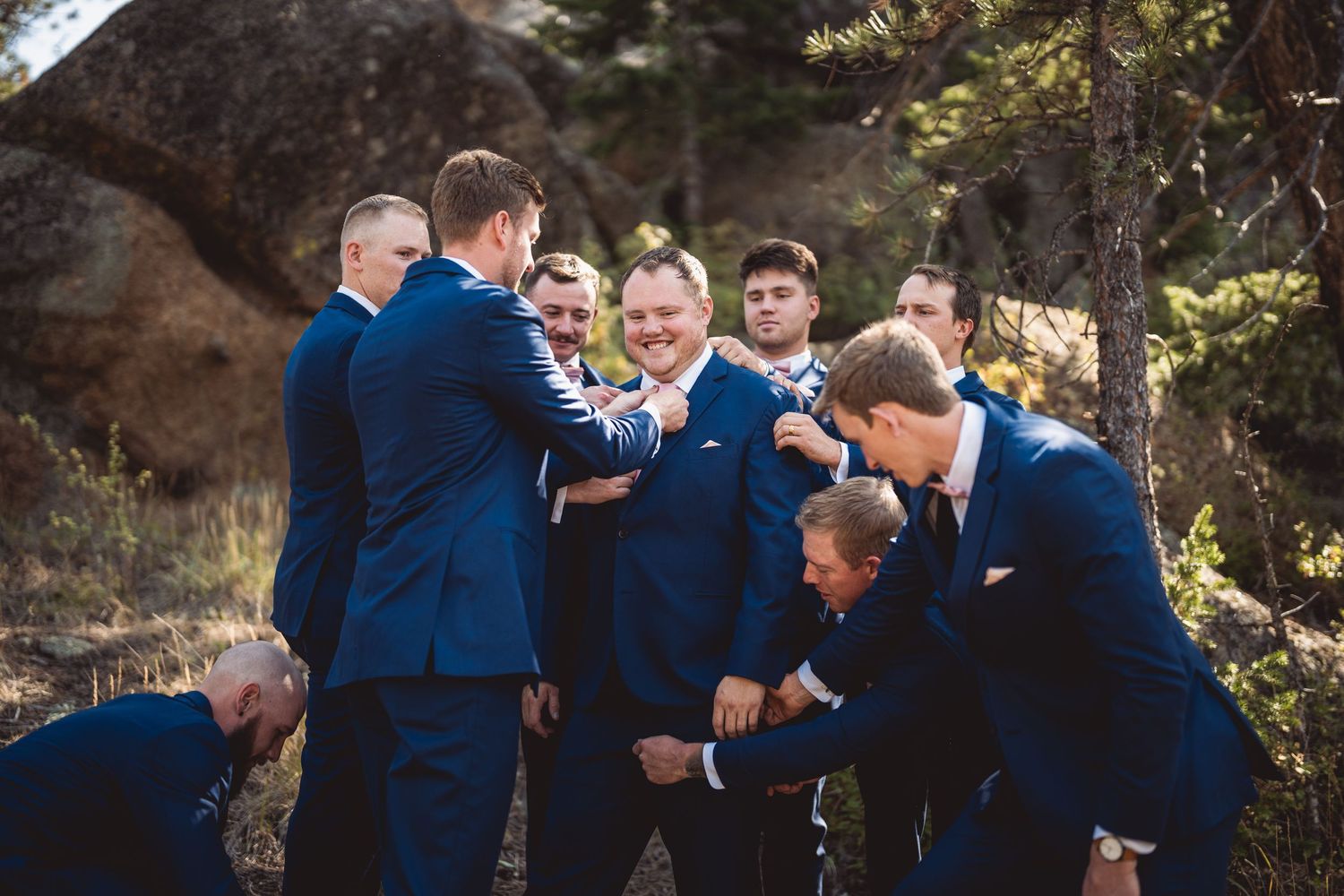 Group photo of wedding party members in coordinated navy attire on a mountain path.