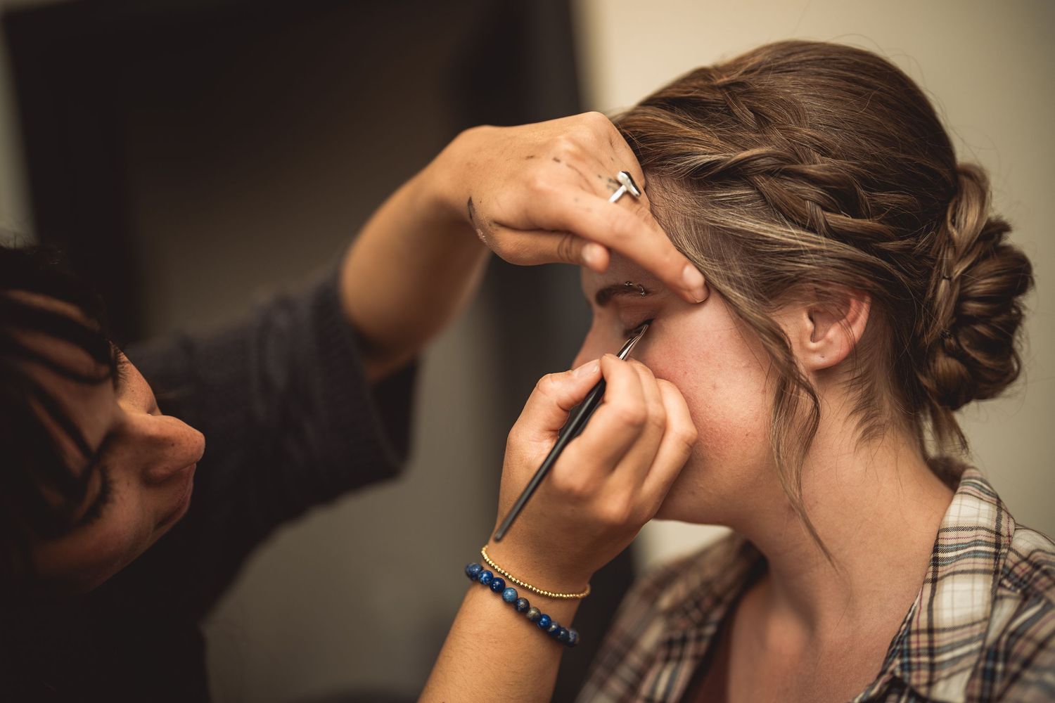 Close-up shots of makeup application process on closed eyes.