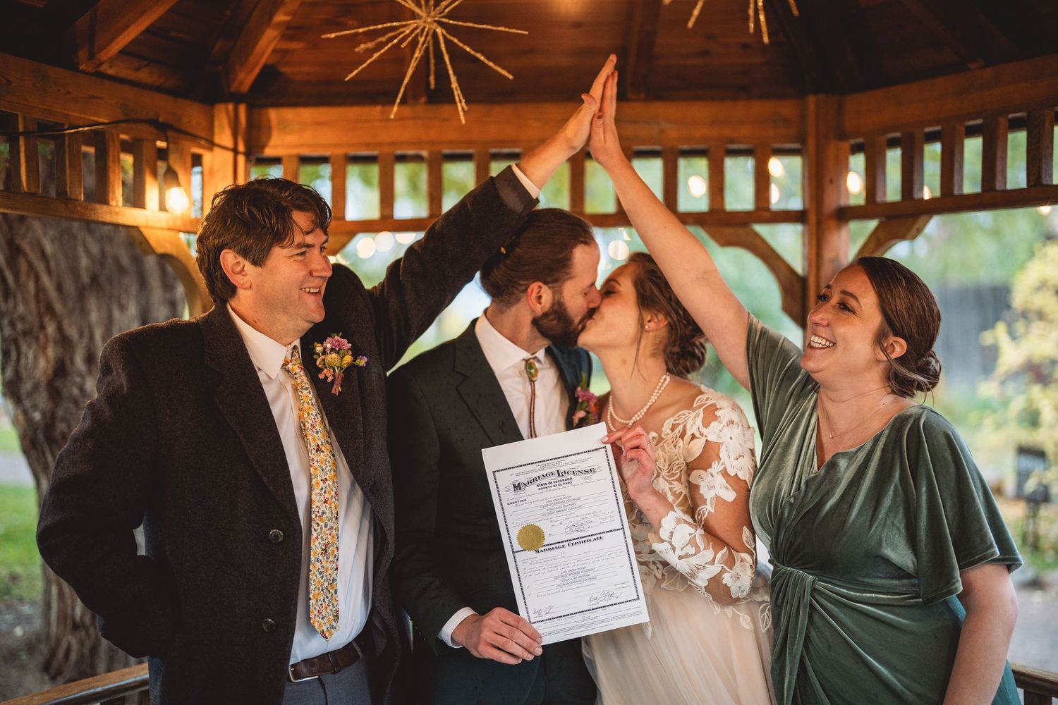 Wedding ceremony celebration under a wooden gazebo with a signed marriage certificate.