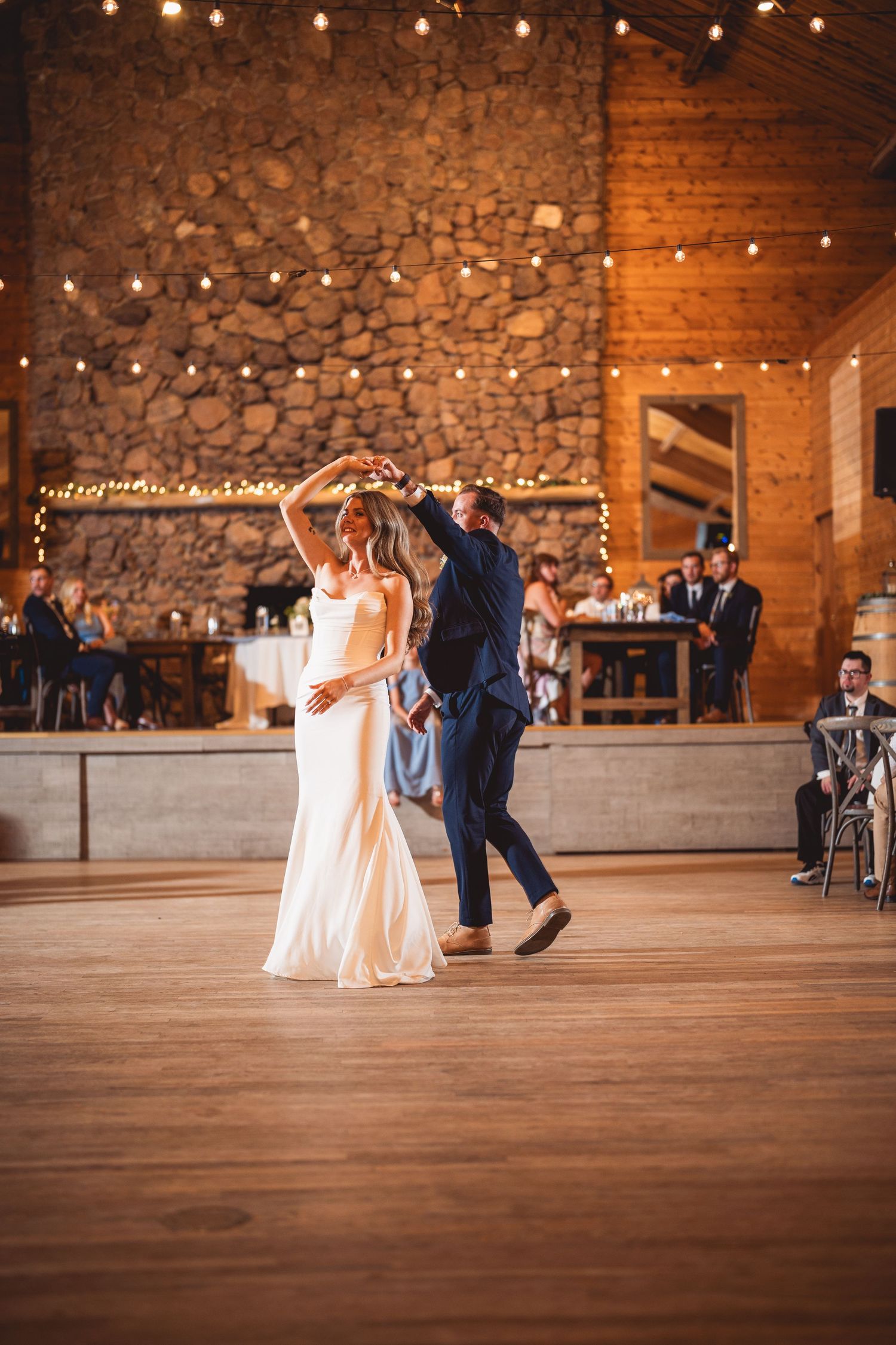 Wedding guests dancing and celebrating in a rustic venue with stone walls.