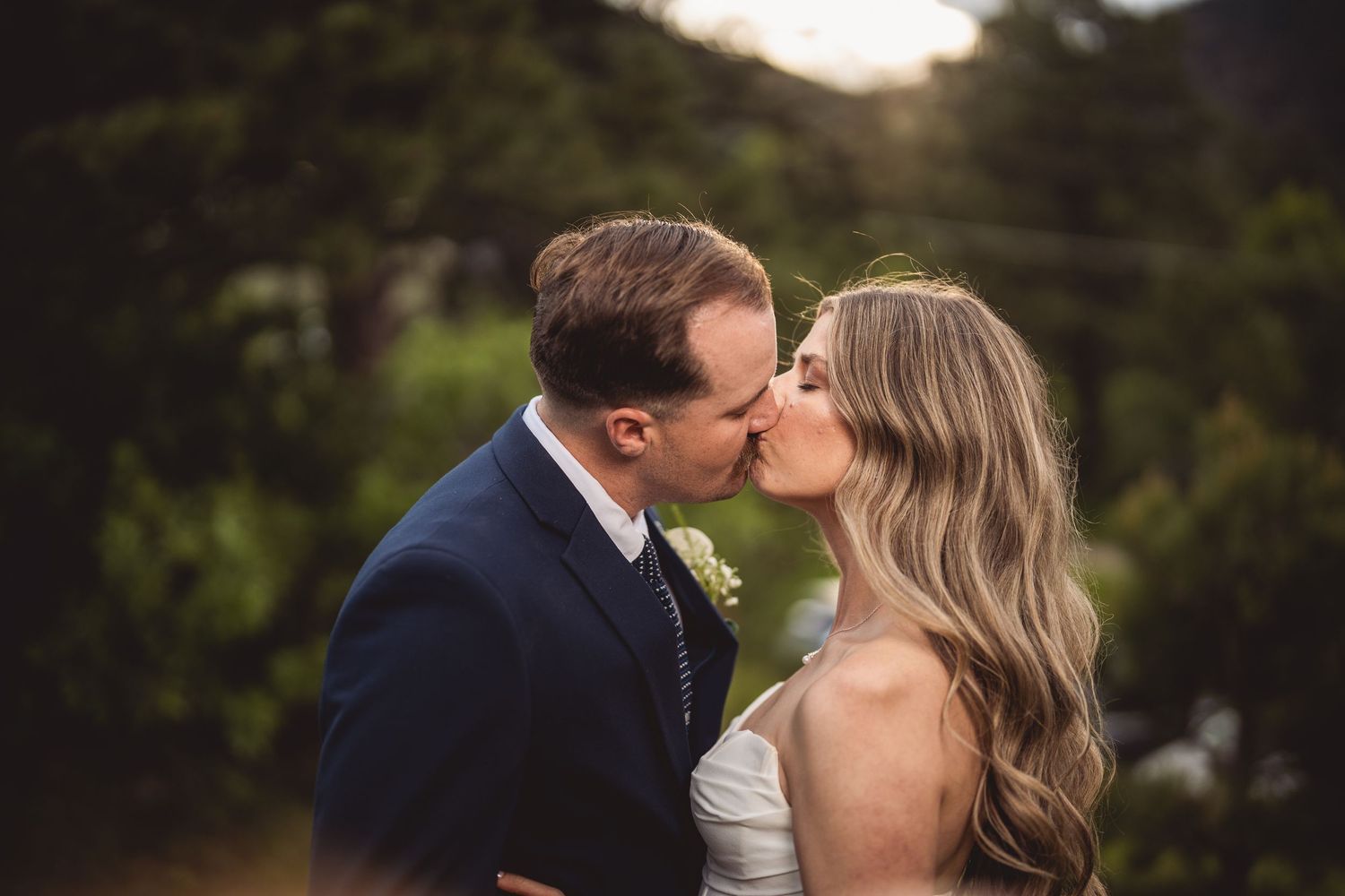 Intimate wedding moment captured outdoors with natural scenery in the background.