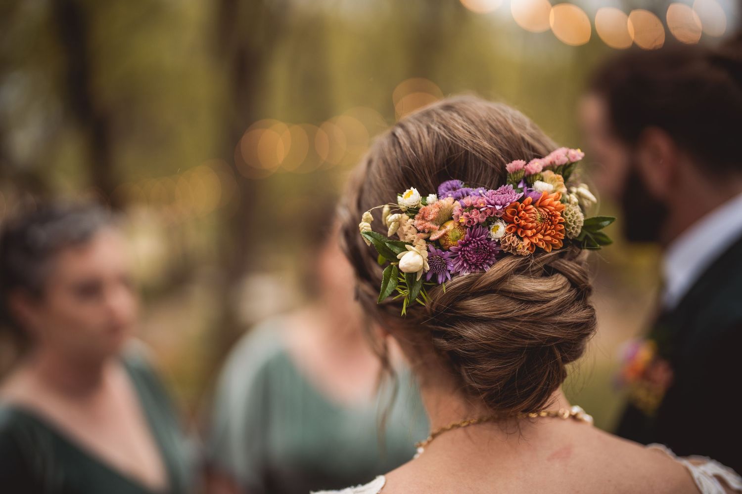 Wedding attendees wearing floral headpieces and elegant attire gathered outdoors.