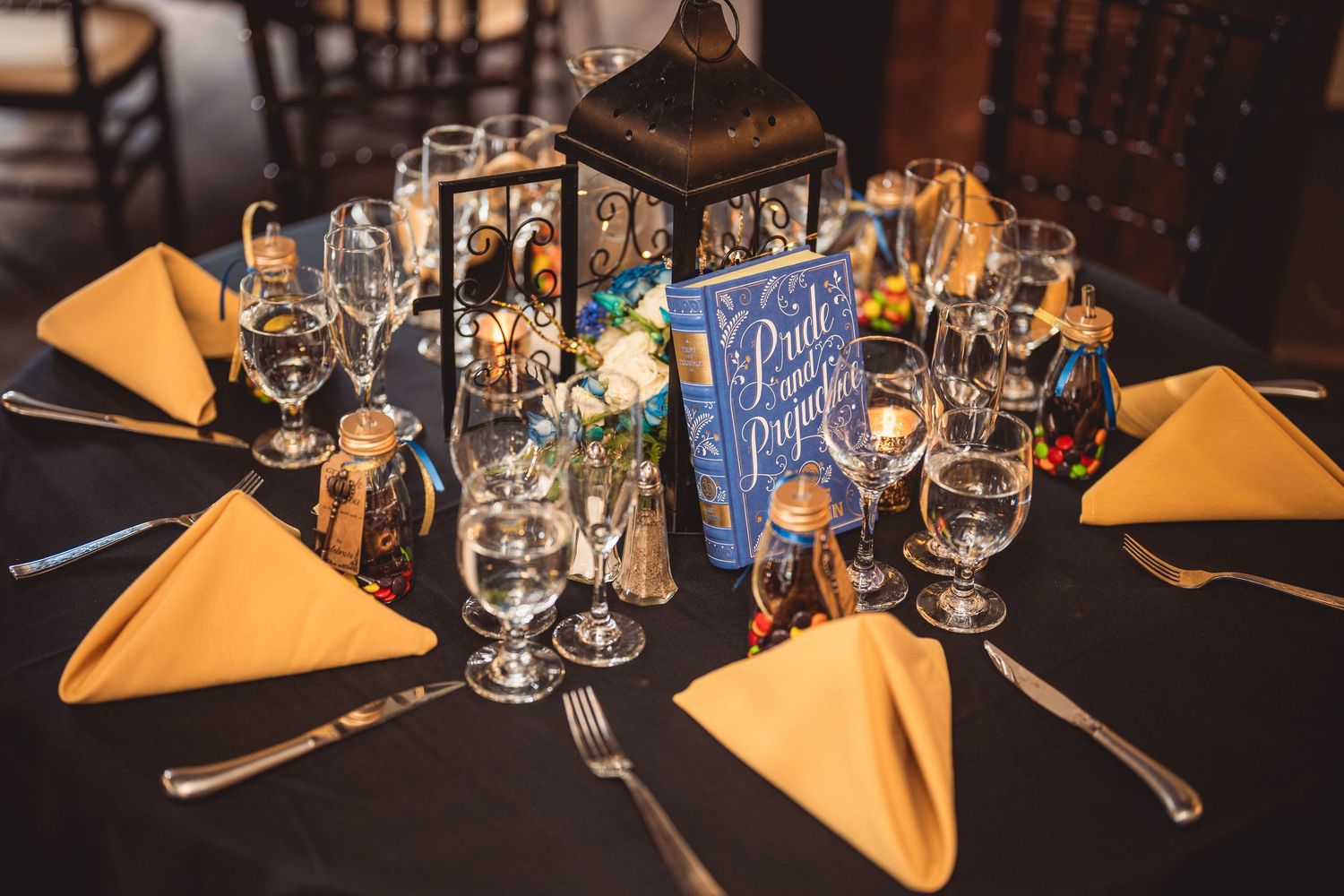 An elegant wedding table setting with orange napkins and vintage lantern centerpieces.