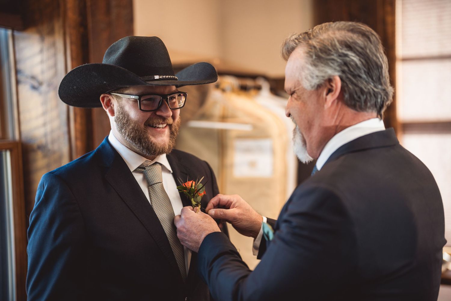 Wedding party members in formal attire chat during an indoor ceremony.