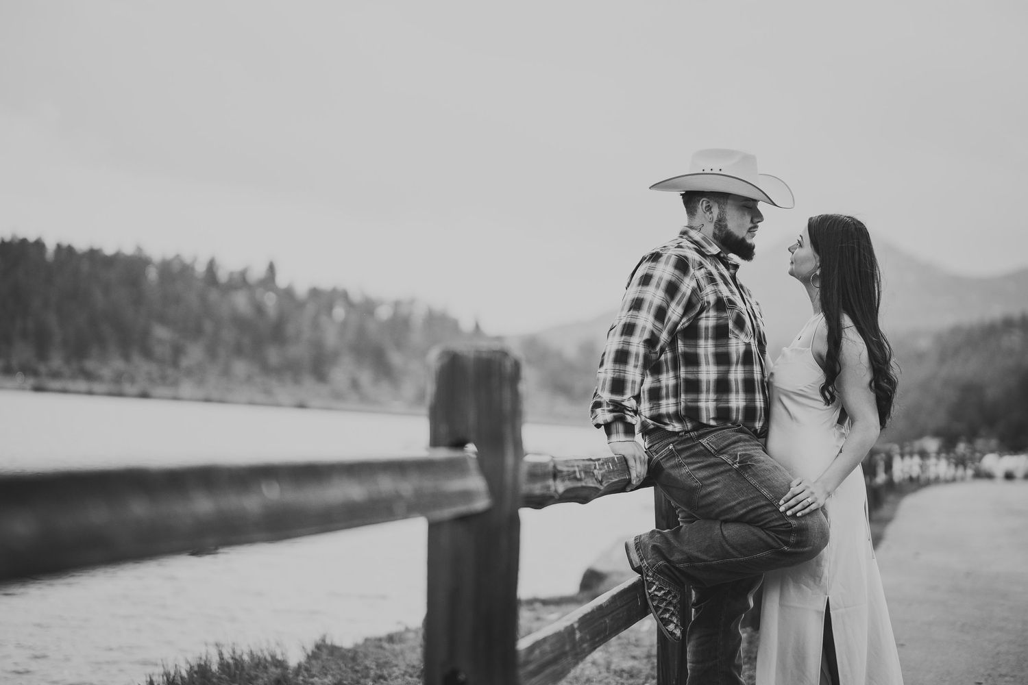 Romantic lakeside engagement photos with mountain and forest scenery.