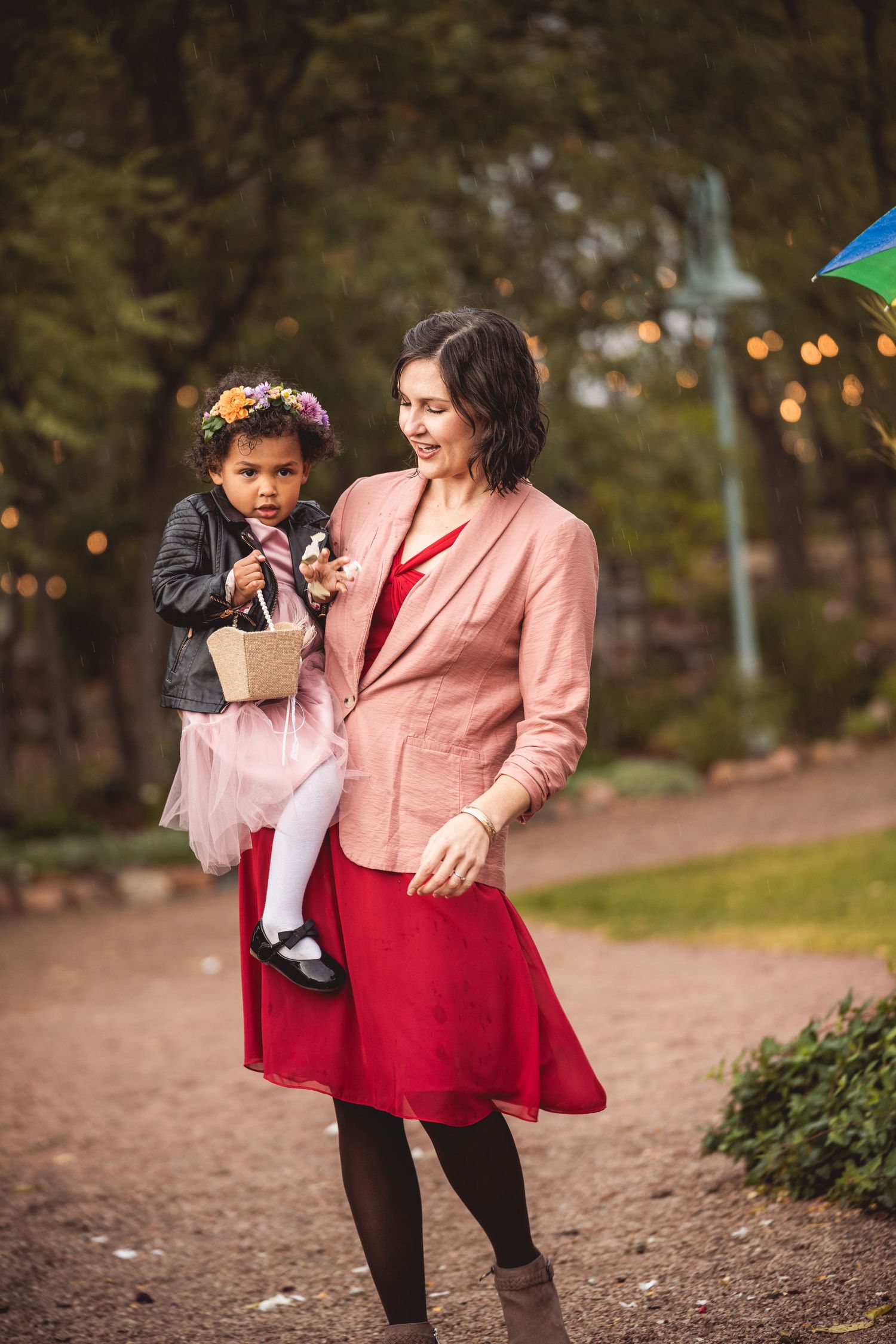 Playful outdoor photo session in a garden path with string lights.