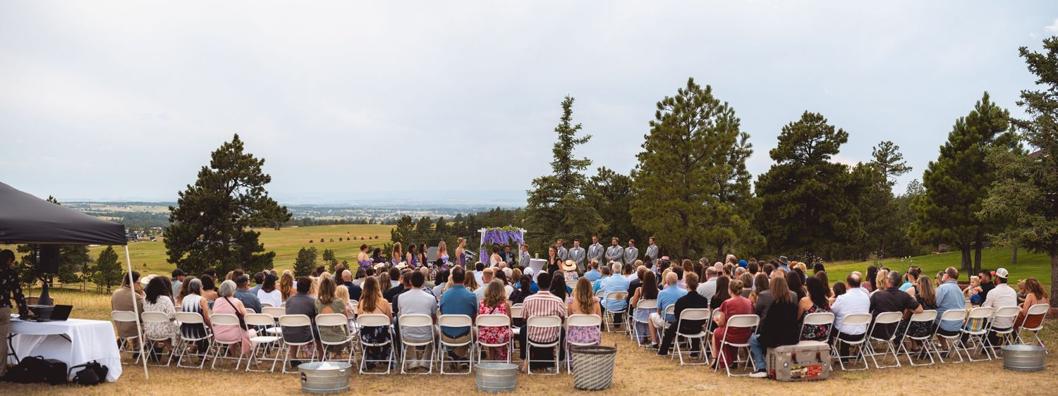 Panoramic view of outdoor wedding ceremony setup in mountain landscape.