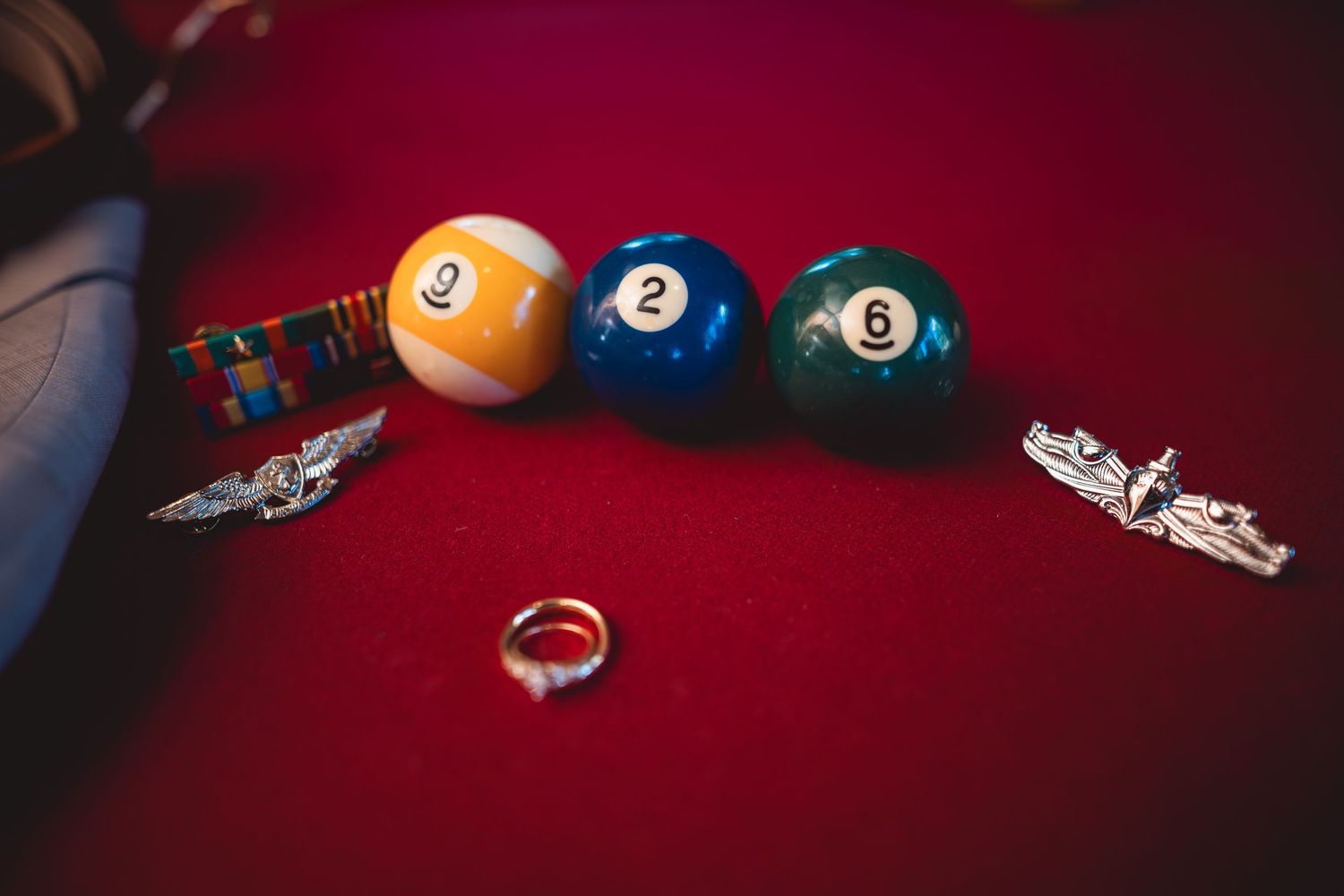 Pool balls and wedding rings artistically arranged on red velvet.