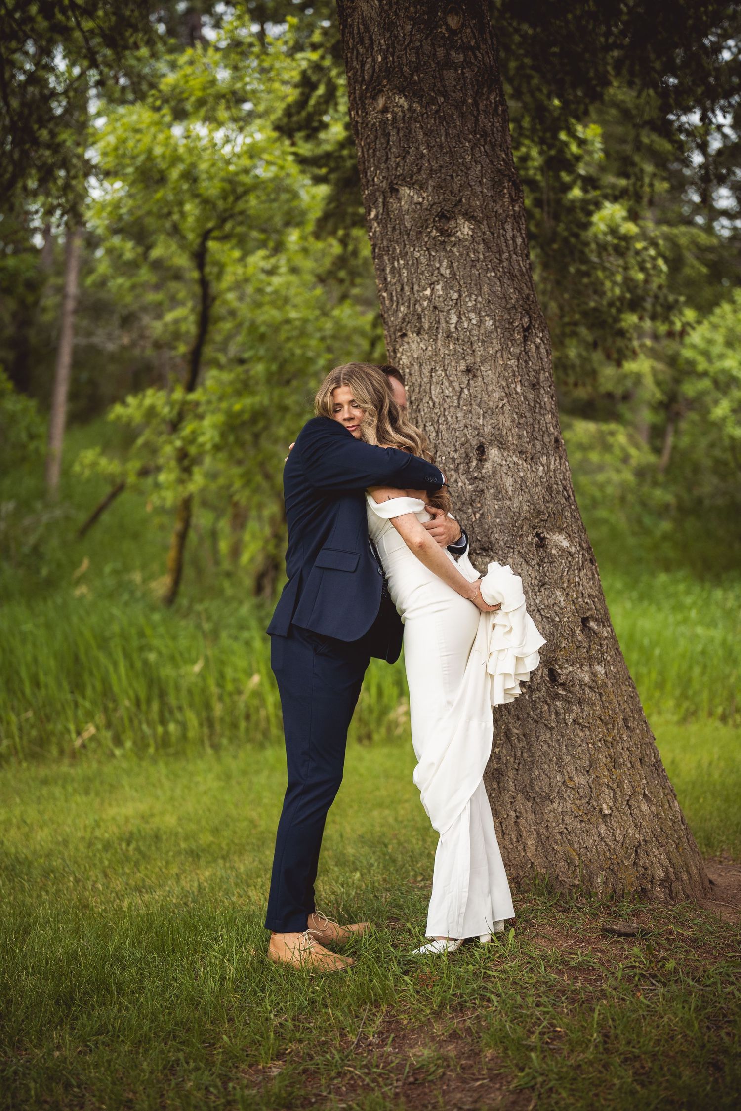 Romantic hide and seek wedding photos taken around a large tree trunk.