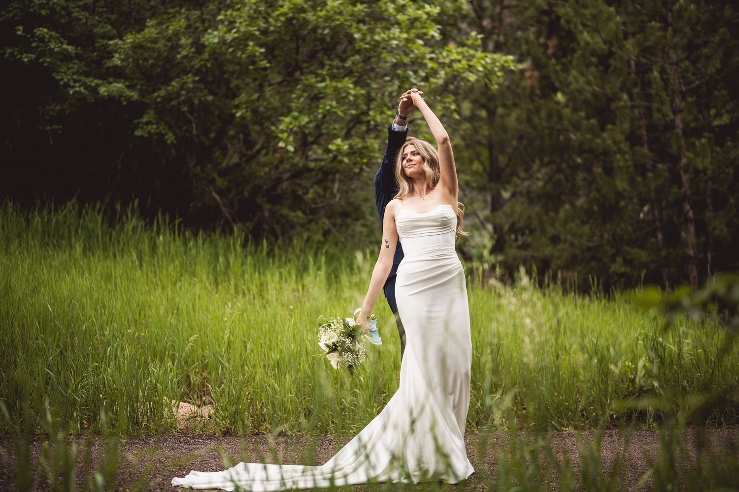 Bride in flowing white dress poses gracefully in outdoor wedding portraits.