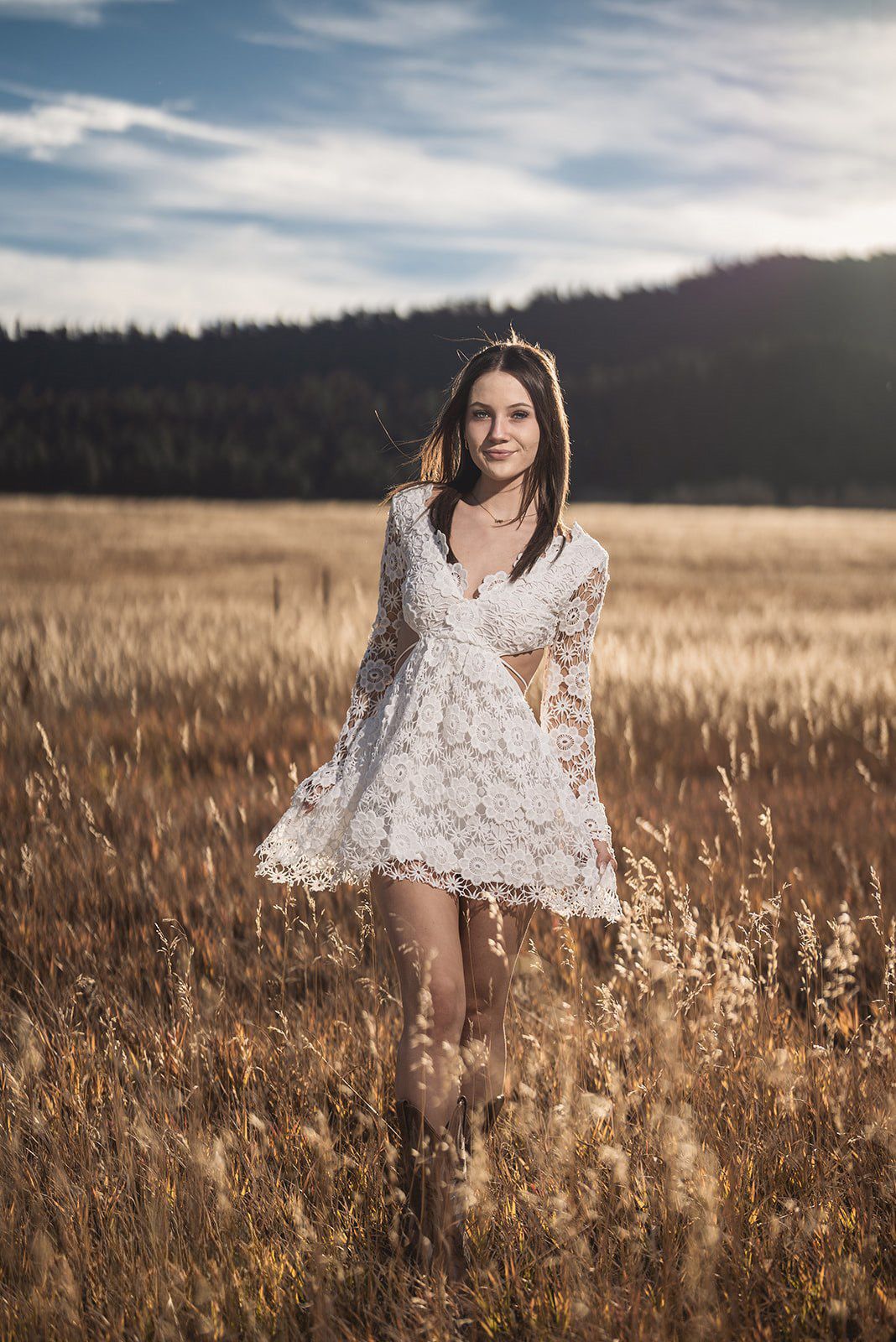 Dreamy outdoor portrait in a golden wheat field with mountains on the horizon.
