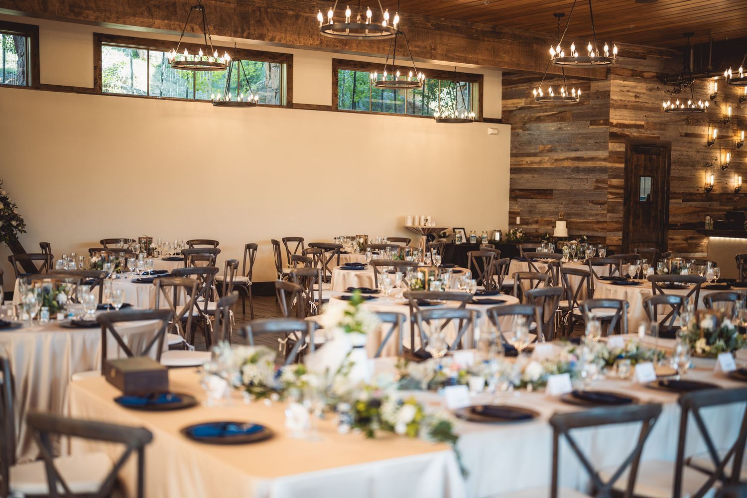 An elegant wedding reception hall with wooden beams and crystal chandeliers.