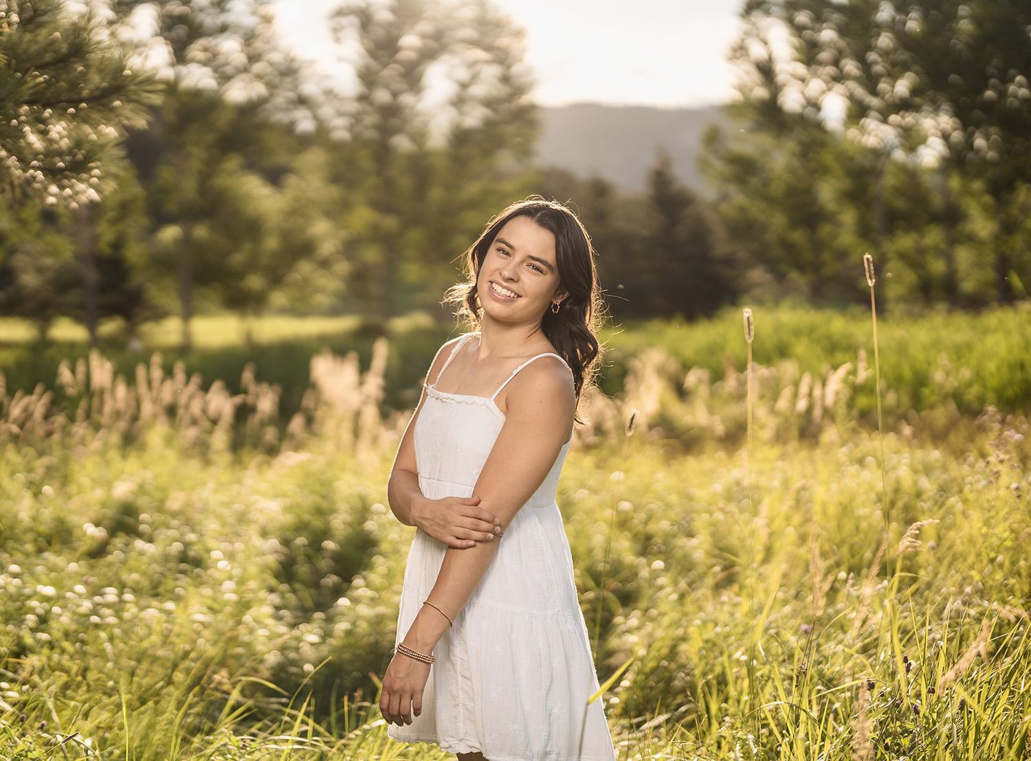 Woman in white dress spins playfully in a sunlit meadow with wildflowers.