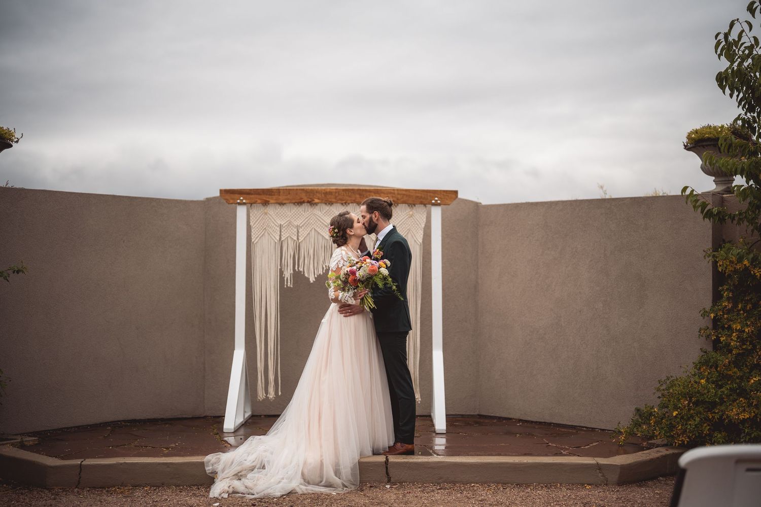 Wedding ceremony panorama featuring white decor and stucco walls under cloudy skies.