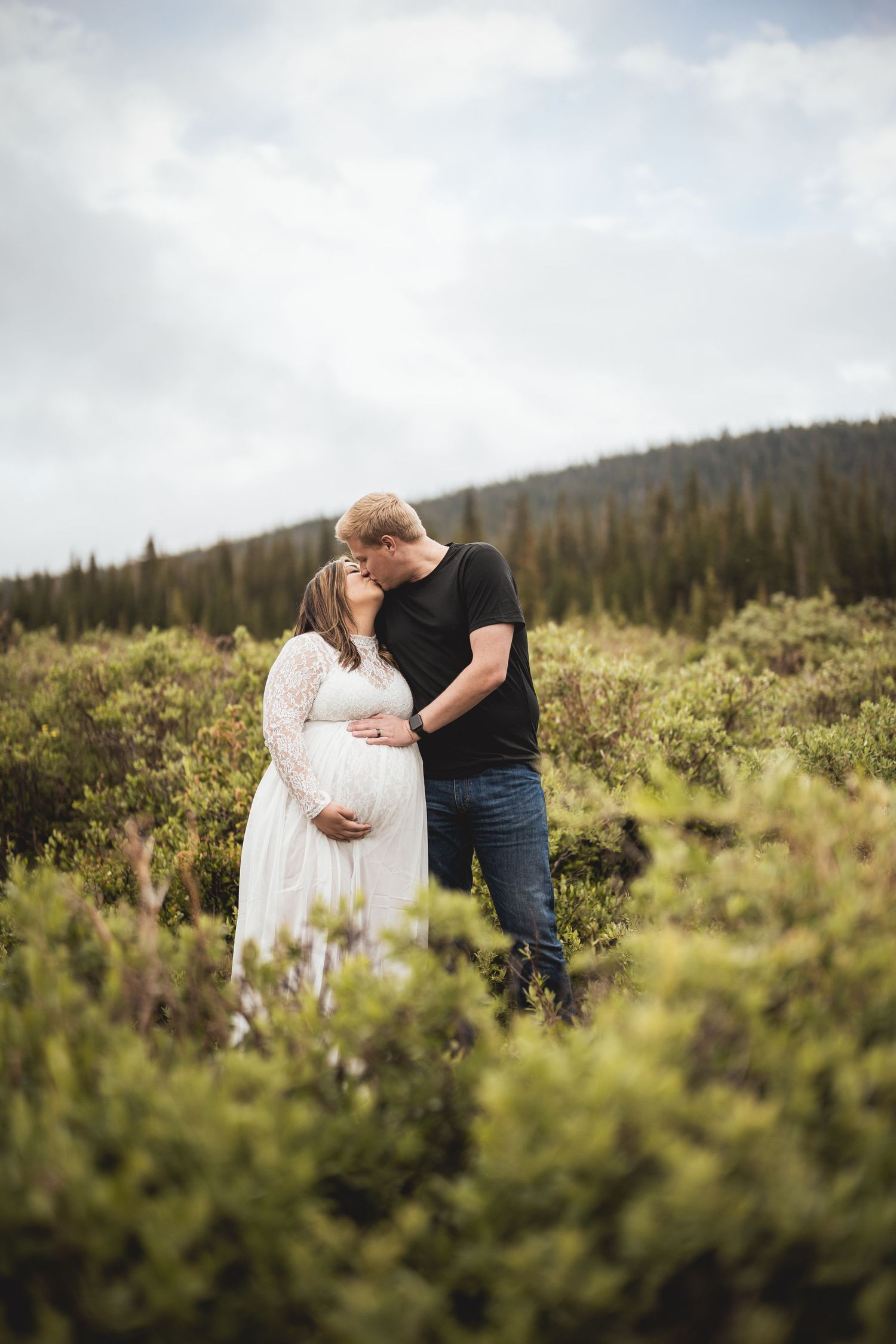 Romantic mountain meadow photography session with wildflowers and evergreen forest.