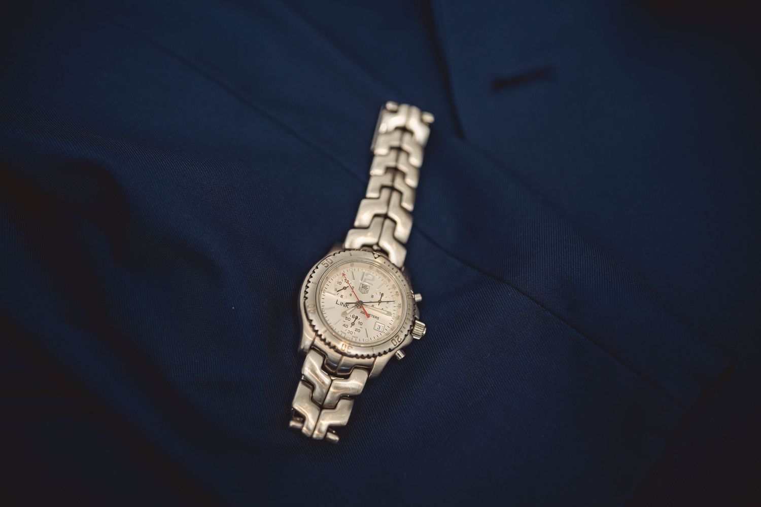 Silver watch with metal band displayed on dark background.