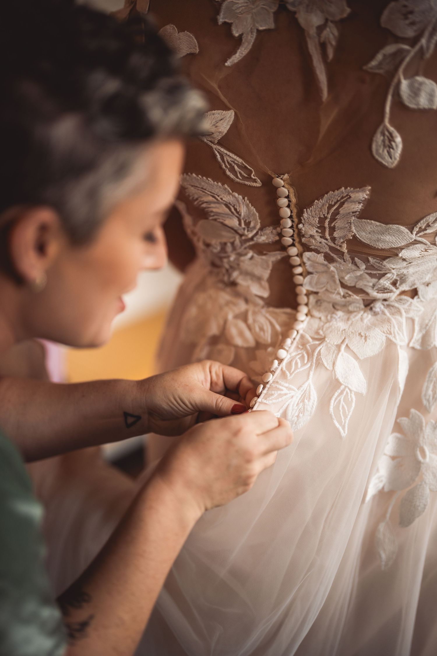 Detailed shot of hands adjusting intricate lace details on a white wedding dress.