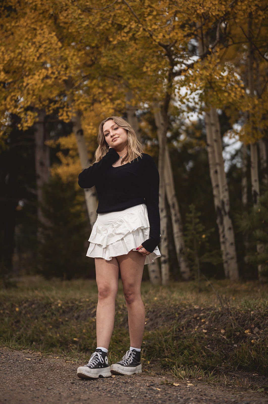 Autumn portrait session in a wooded park with fallen leaves and black and white outfit details.