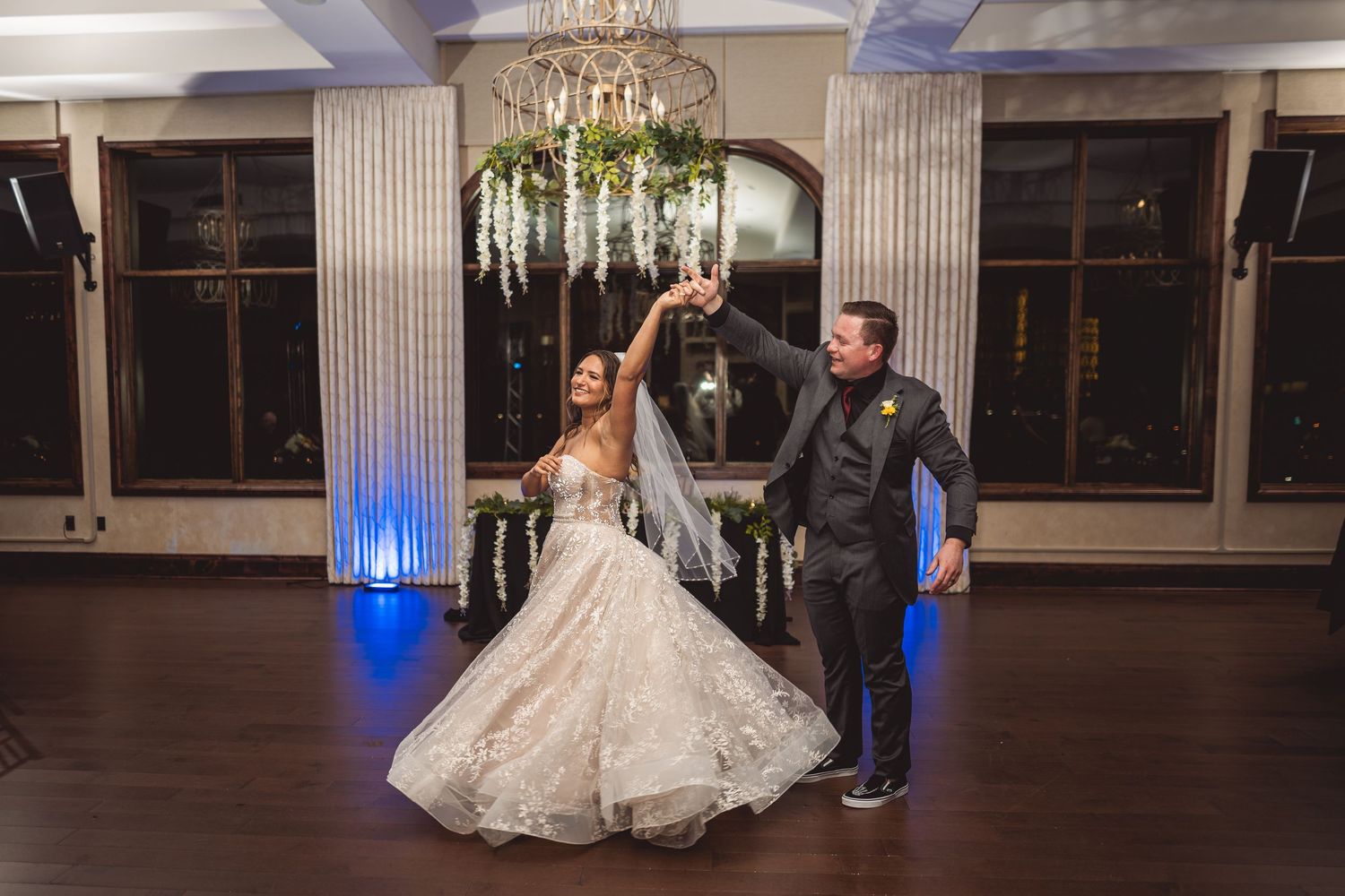 Ballroom decorated for a wedding reception with chandelier and blue accent lighting.