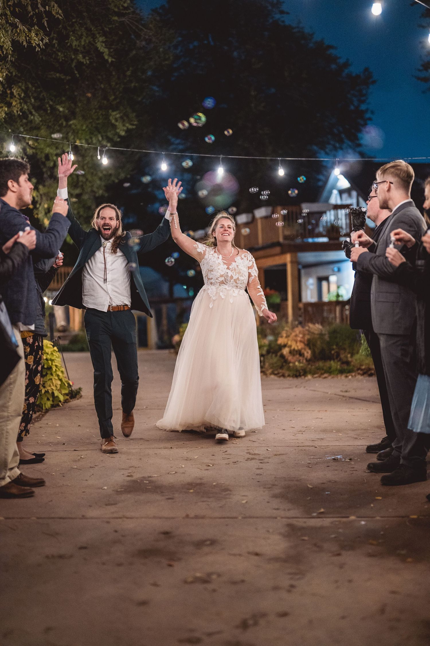 Wedding guests form a celebratory exit line at night with sparklers for the newlyweds.