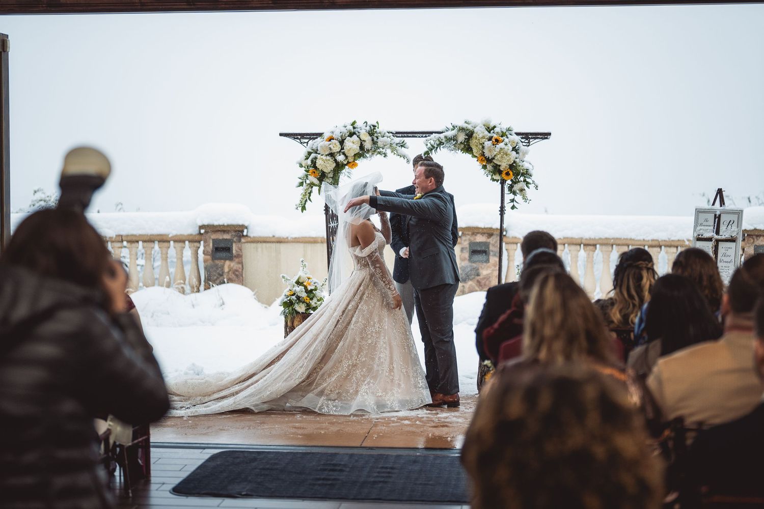 Wedding ceremony with a floral arch and long veil trailing behind.