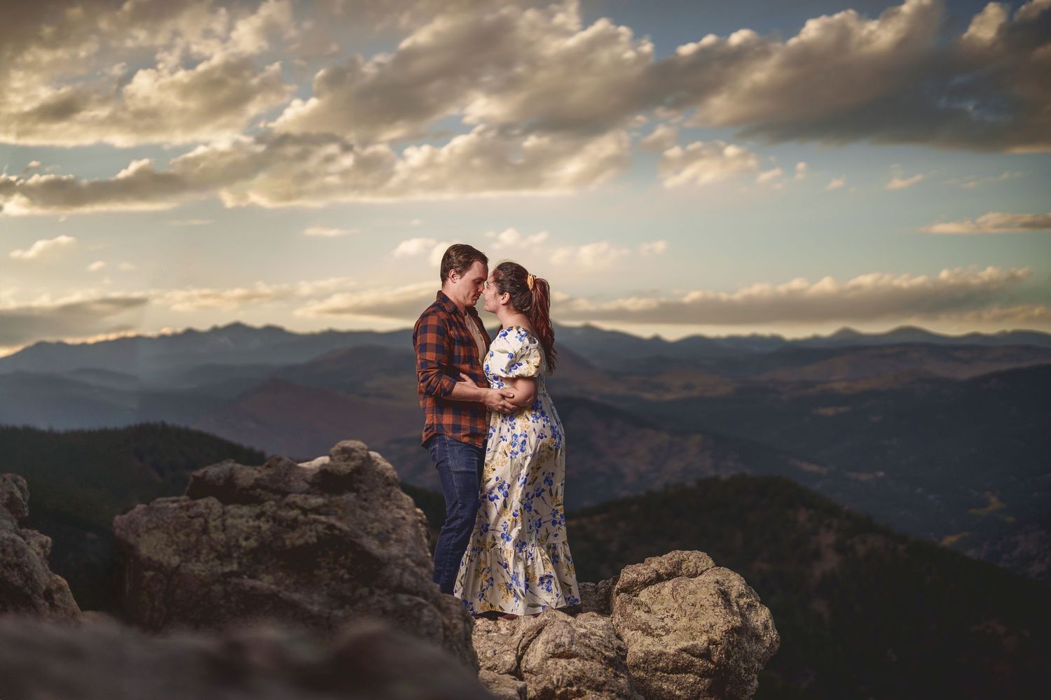 Dramatic mountain vista with clouds creates stunning backdrop for couple's engagement portraits.