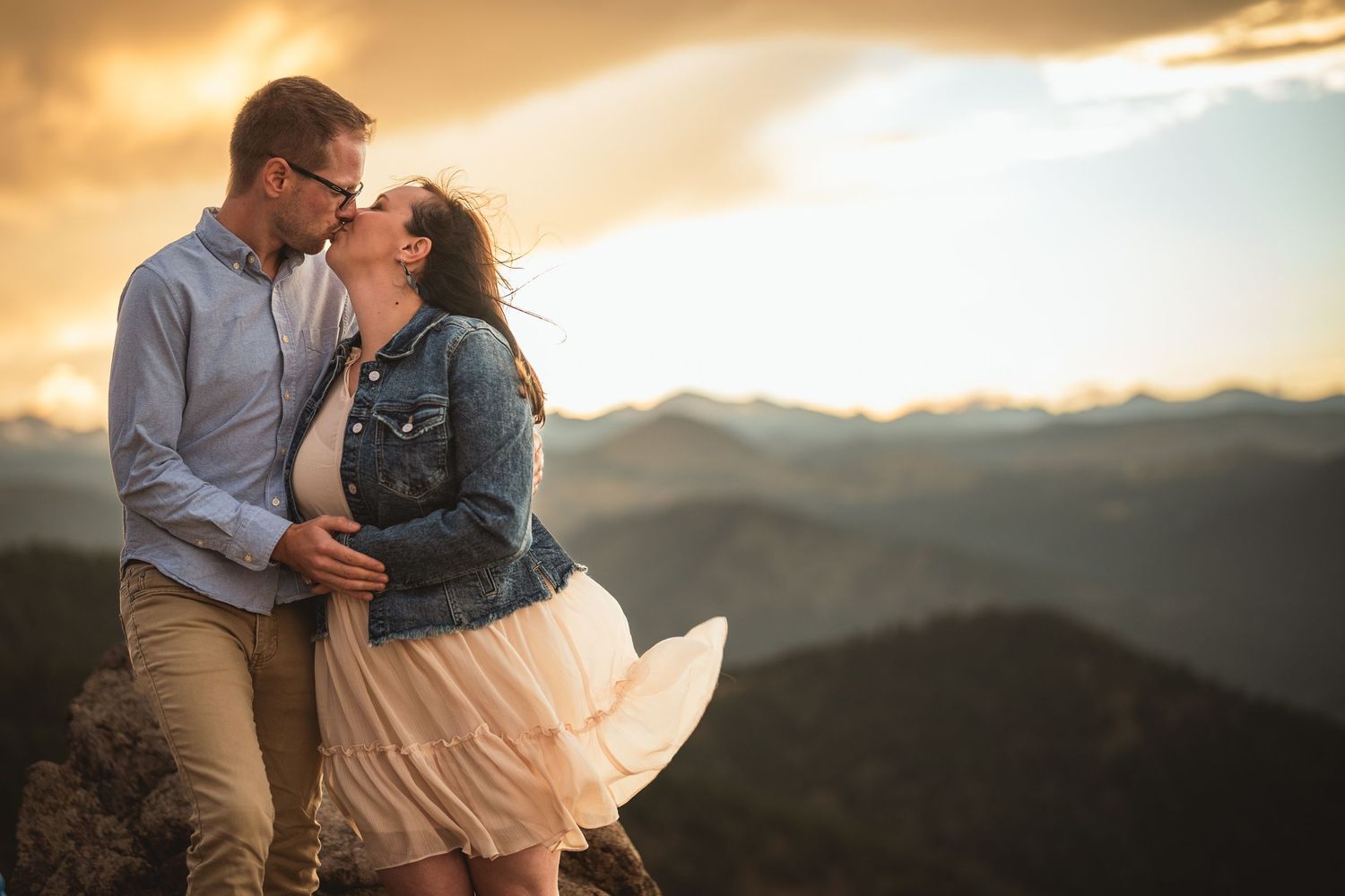 Silhouettes against a golden mountain sunset create a dramatic romantic moment.