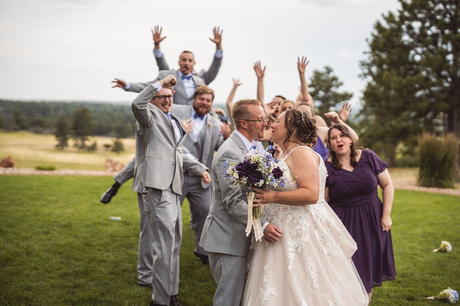 Wedding group photo with bridal party celebrating energetically outdoors.