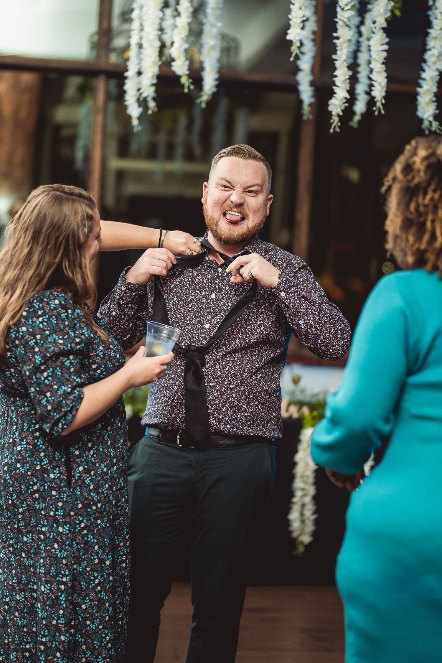 Wedding guests dancing and celebrating during reception under hanging floral decorations.