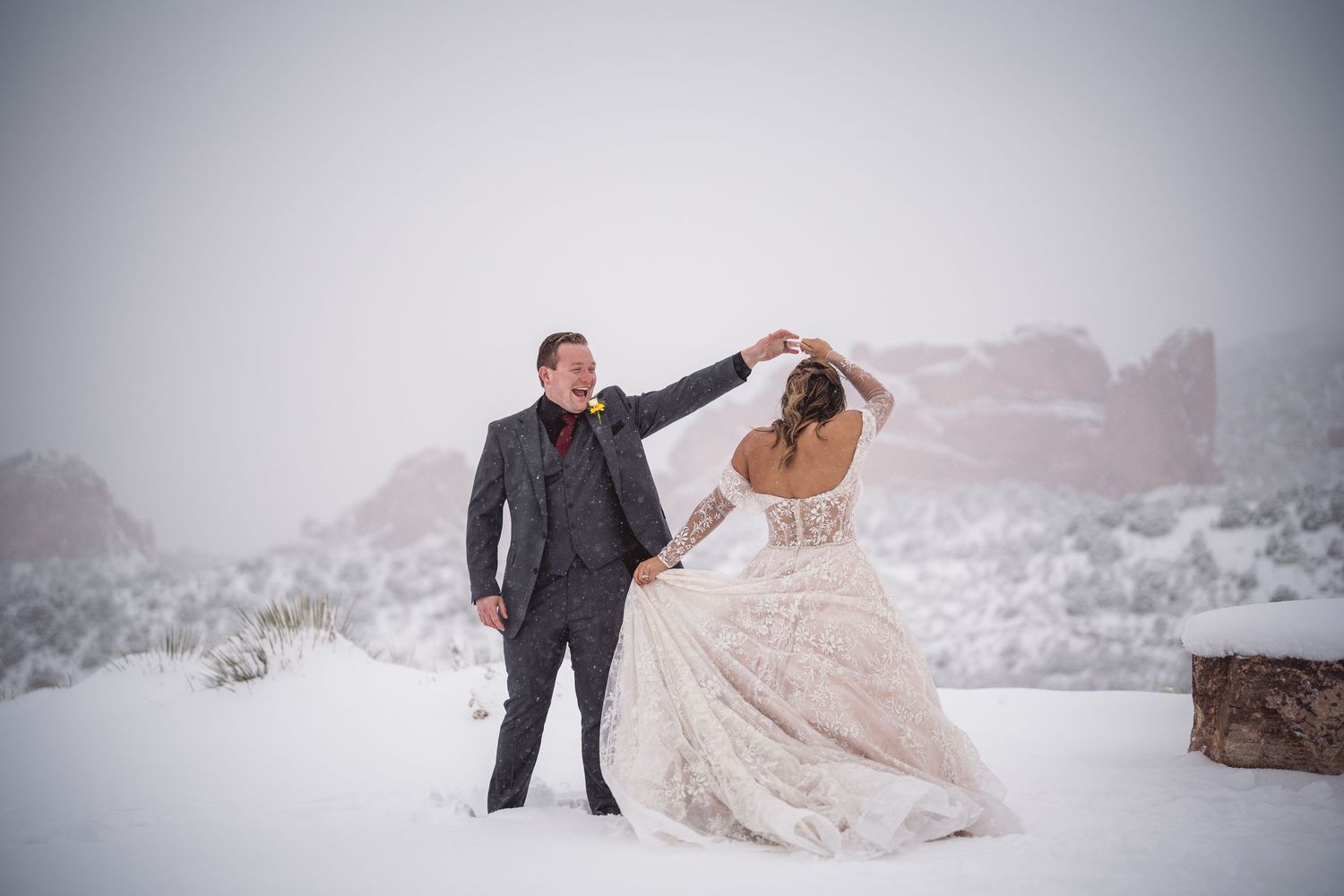 A couple dances together in a snowy winter landscape wearing formal attire.
