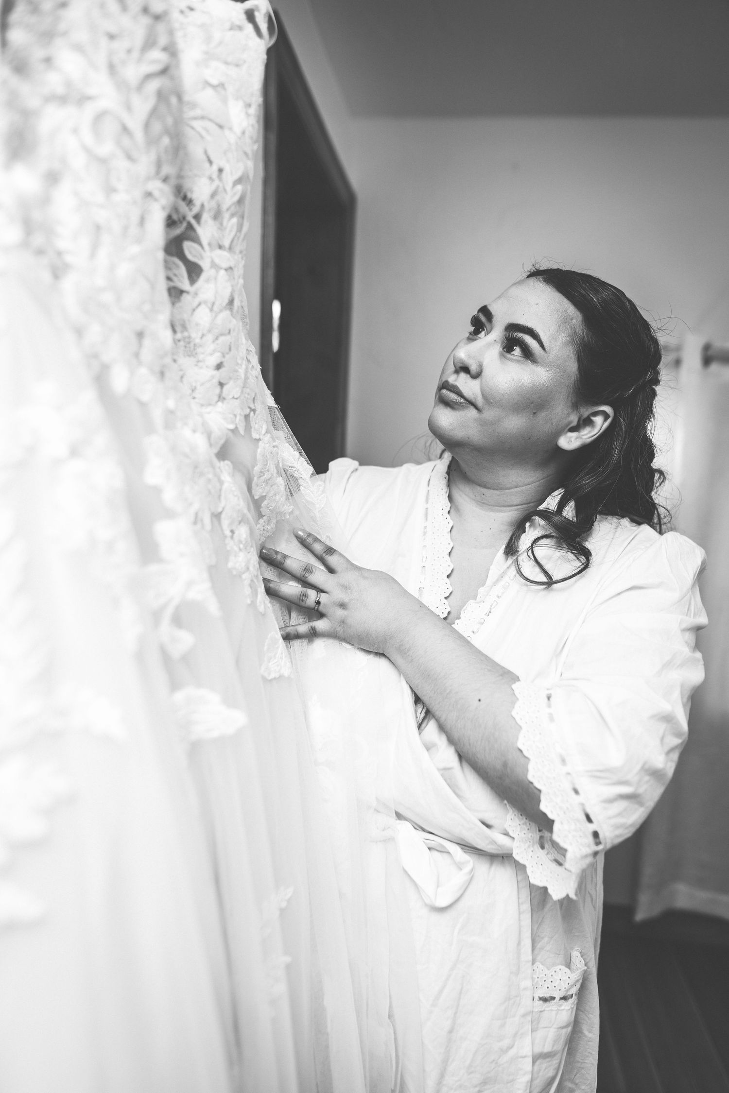 Person handling delicate white lace details of wedding dress.