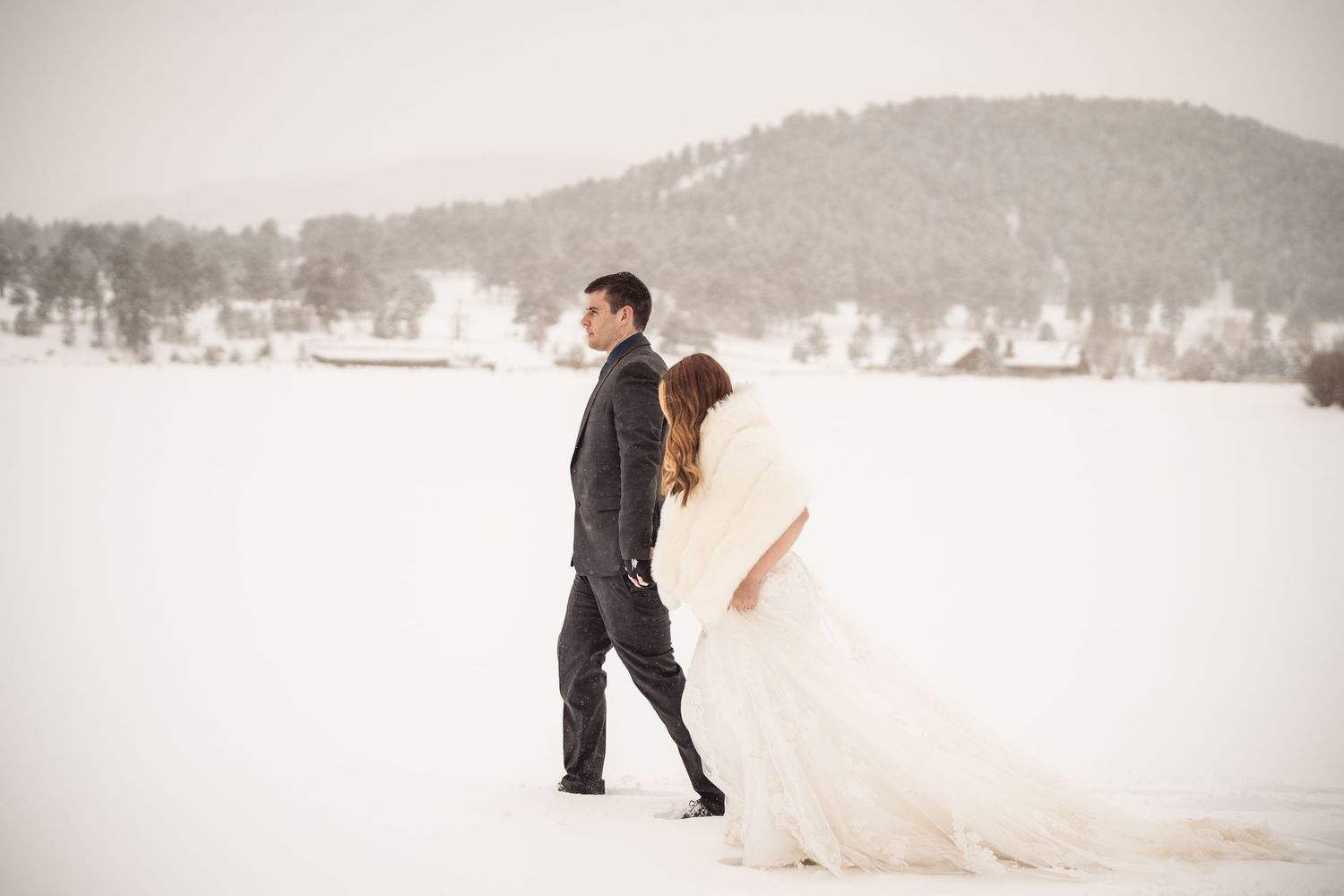 Snowy winter wedding photoshoot with mountain landscape in the background.