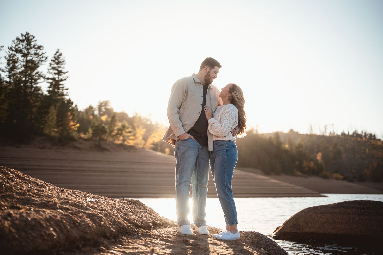 Romantic sunset moment captured on rocky terrain near water.