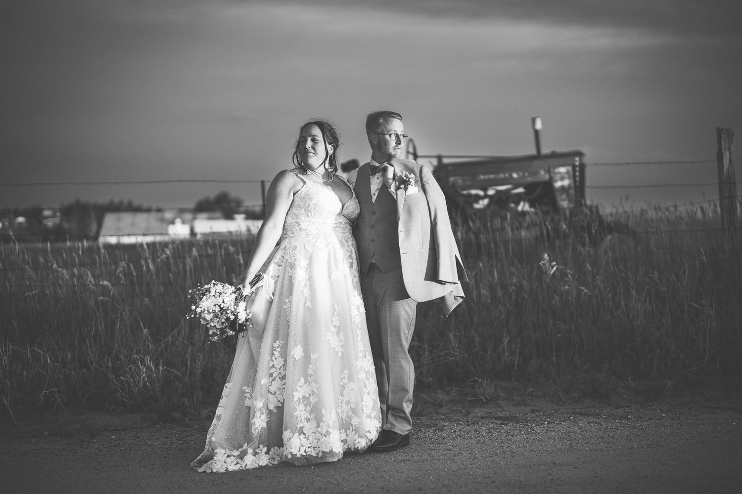 Black and white portrait of couple walking together on country road at dusk.
