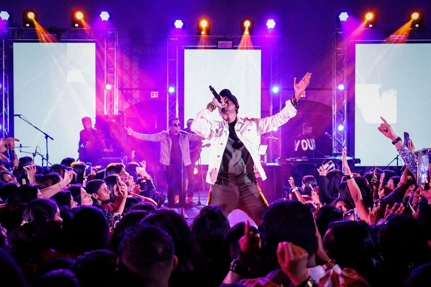 Musical show. A man singing under flashy purple lights. crowd cheering.