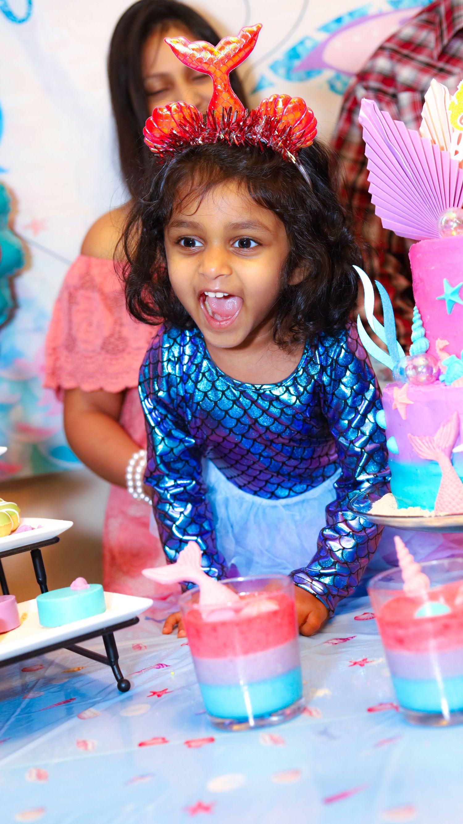 A birthday girl wearing a blue dress excited.