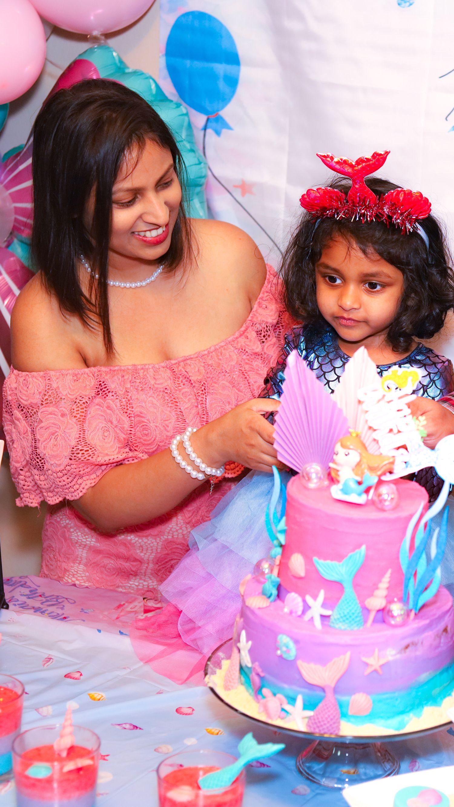 A birthday party photo. A woman and a kid standing behind the cake.
