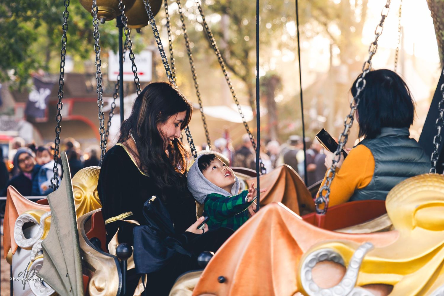 Two women and a kid riding a carousel.