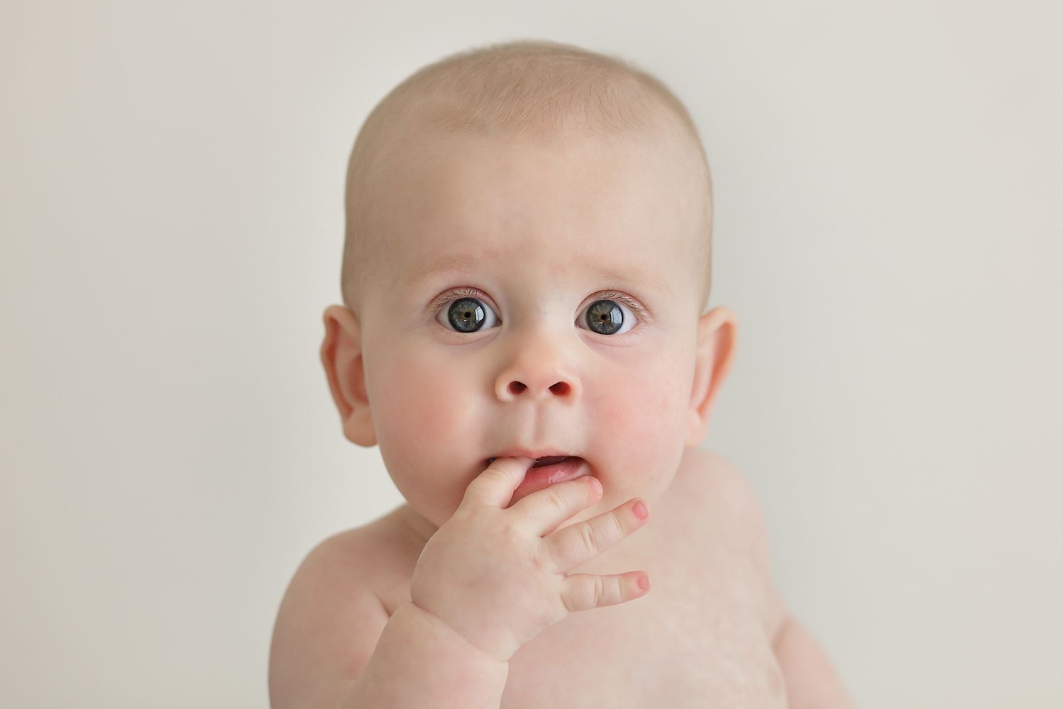 Baby with bright eyes looking directly at camera against white background.