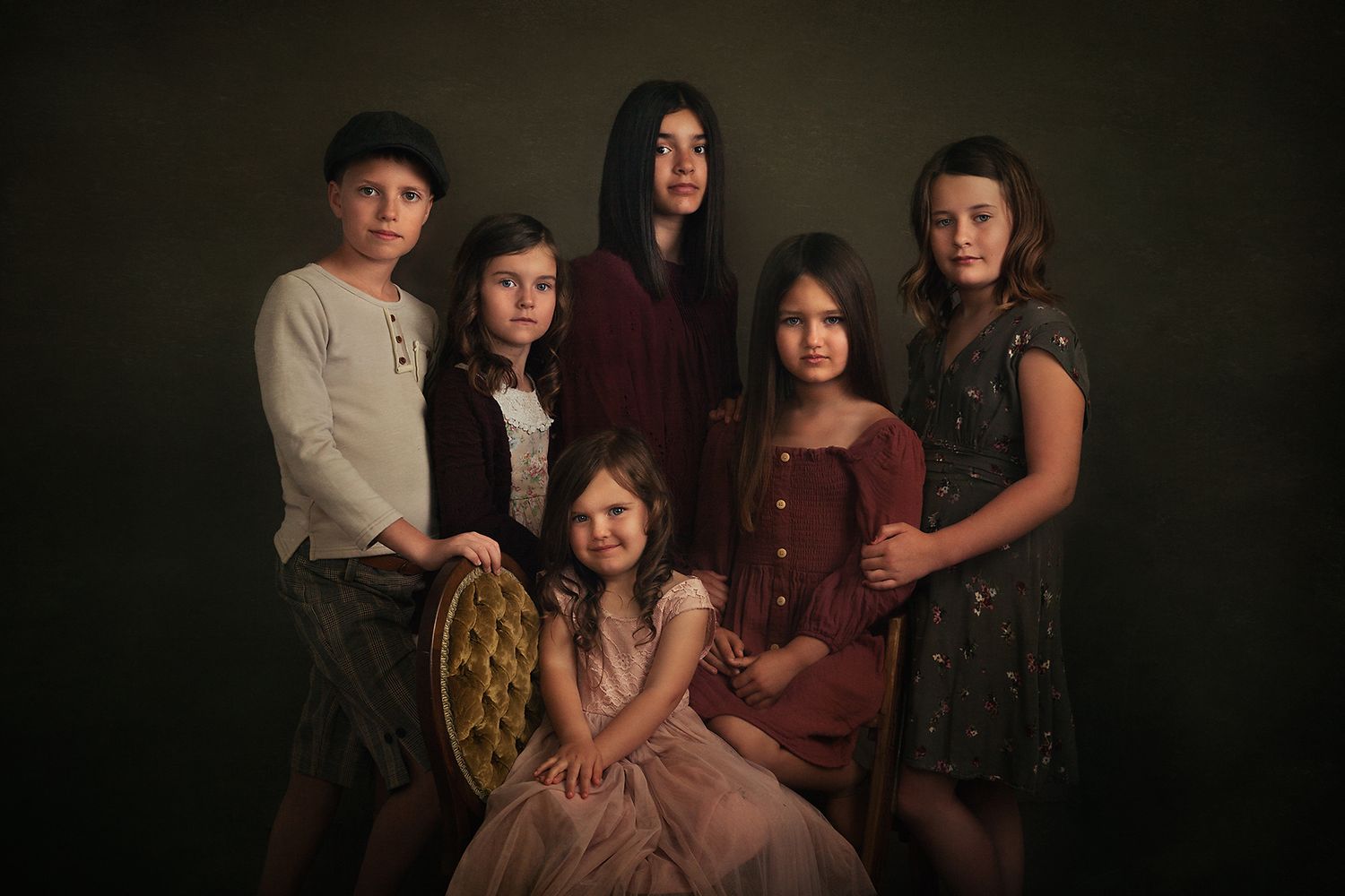 Moody family portrait session against dark background with vintage styling.