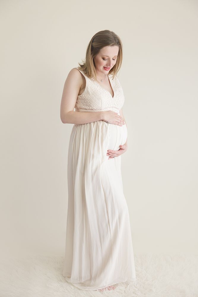 Ethereal maternity portraits in a flowing white dress against a minimalist background.
