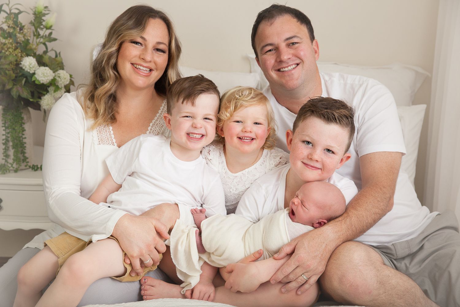 Bright family portrait session on white backdrop with casual styling.