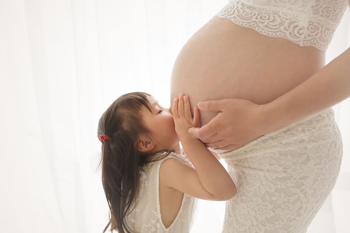 Sweet mother-daughter maternity photos in matching white dresses.