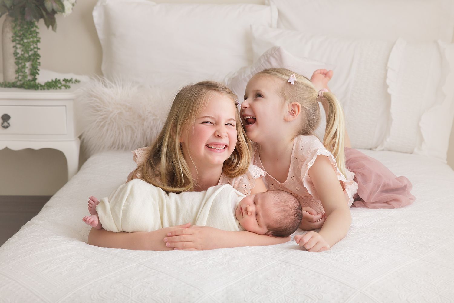 Two young children sharing a joyful laugh while lying on a white bed.